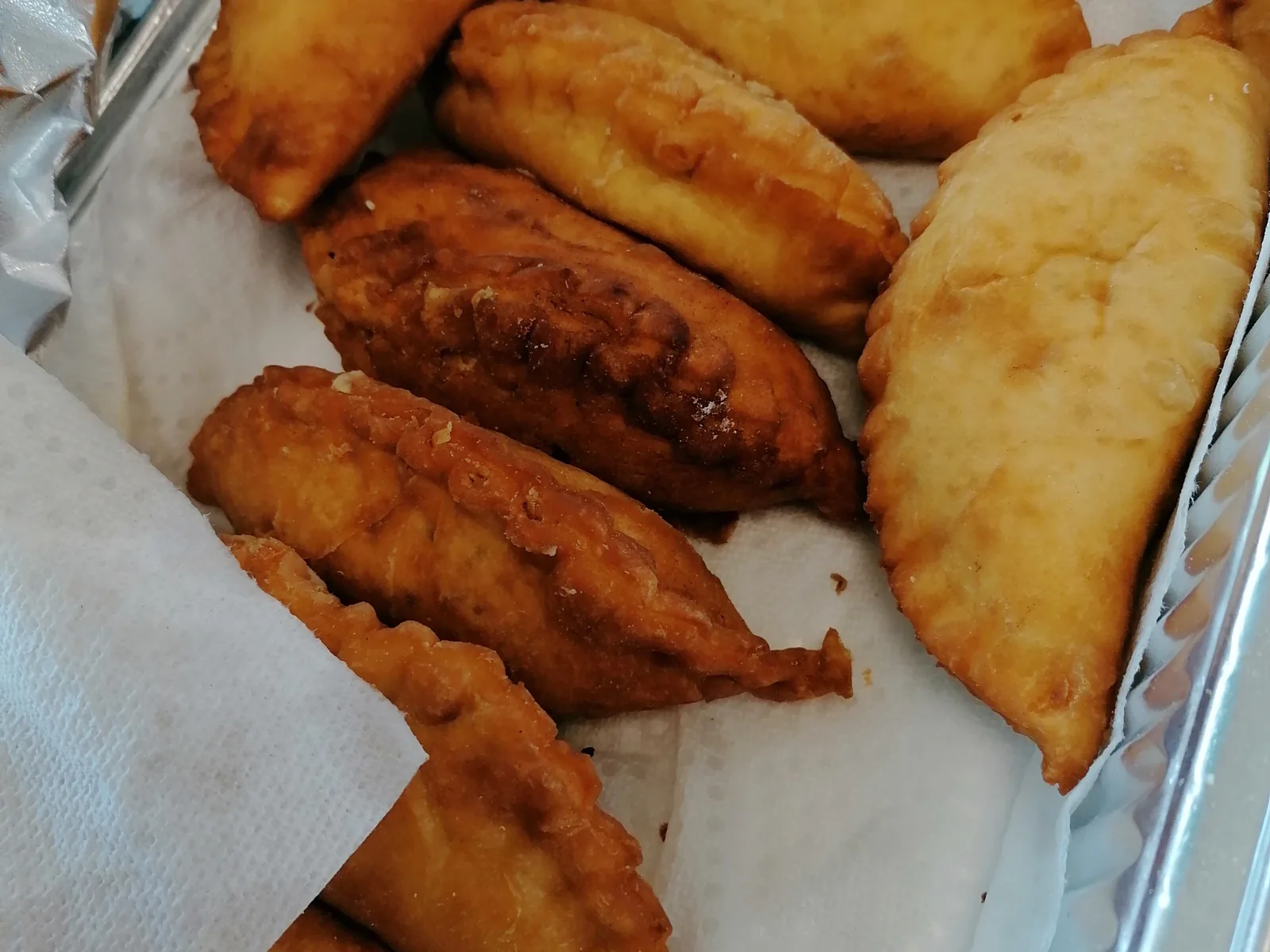 A tray of golden, crescent-shaped fried pastechi, the classic Aruban snack pastry